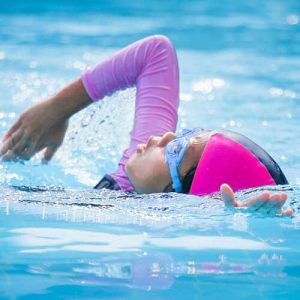 little girl in a swimsuit while doing strokes in the water