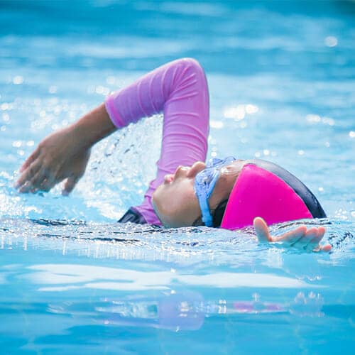 little girl in a swimsuit while doing strokes in the water