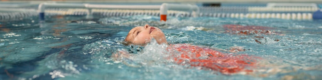little girl swimming with her head above the water