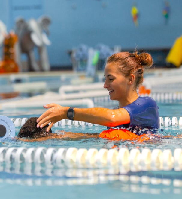 female swim coach guiding a child in the pool