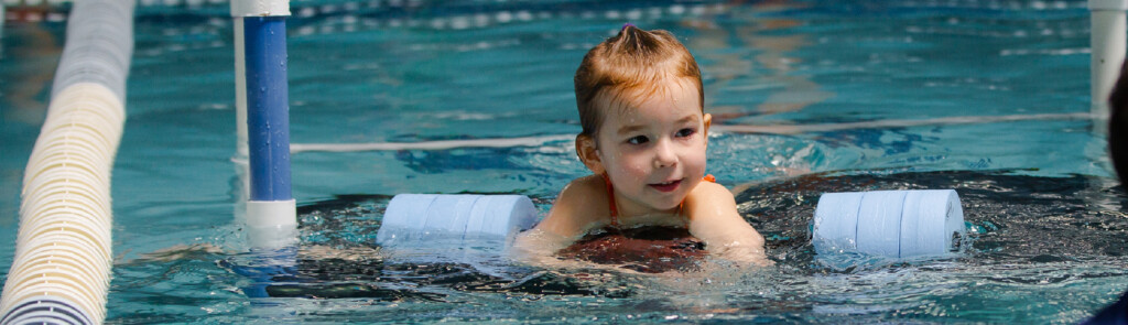a child floating in the water with inflatables