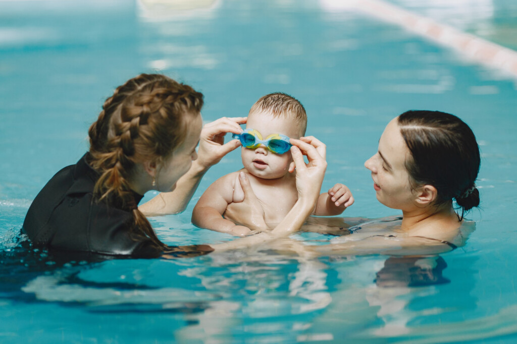 young child held by their parent in a swimming pool