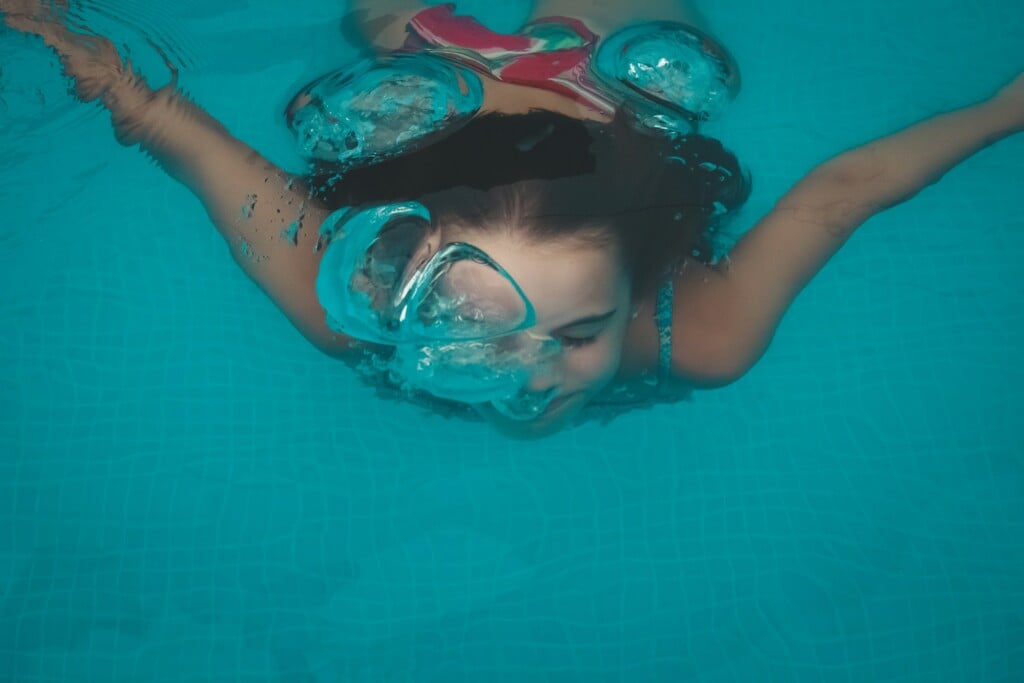 Kid swimming while blowing bubbles from underwater