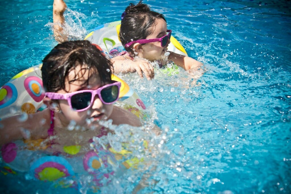 Two kids freestyle swimming a pool