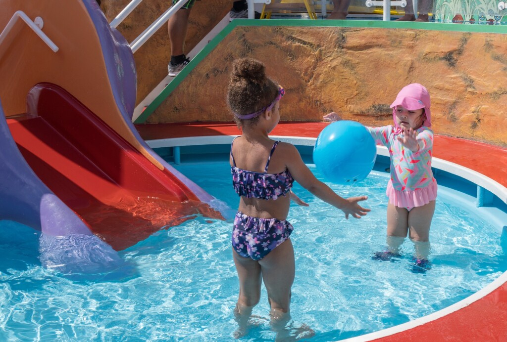 two kids playing catch the ball in the pool