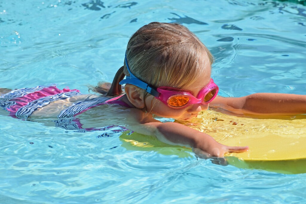 toddler using a kickboard in the pool