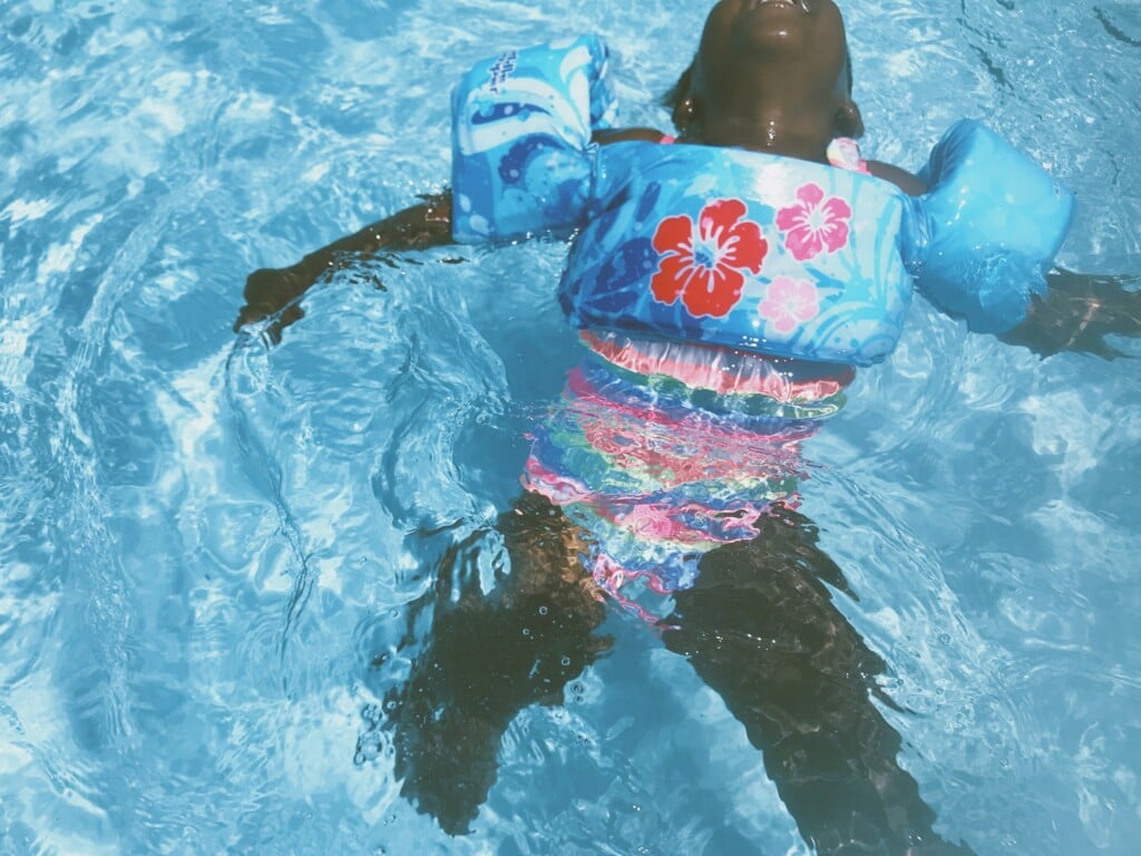 A young girl swimming backstroke in a pool