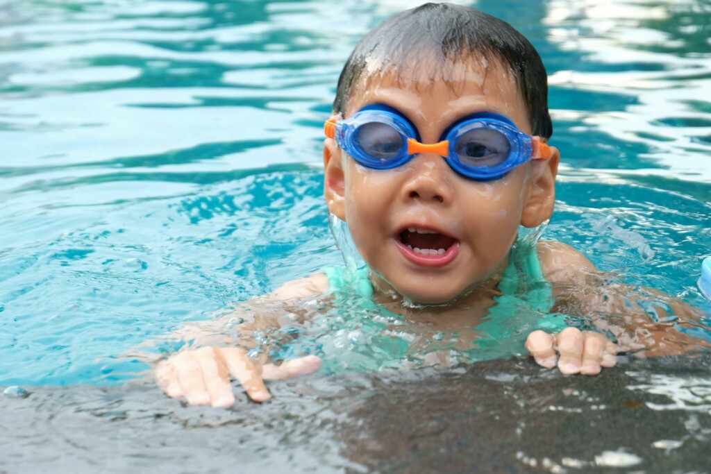 child in pool wearing blue swim googles